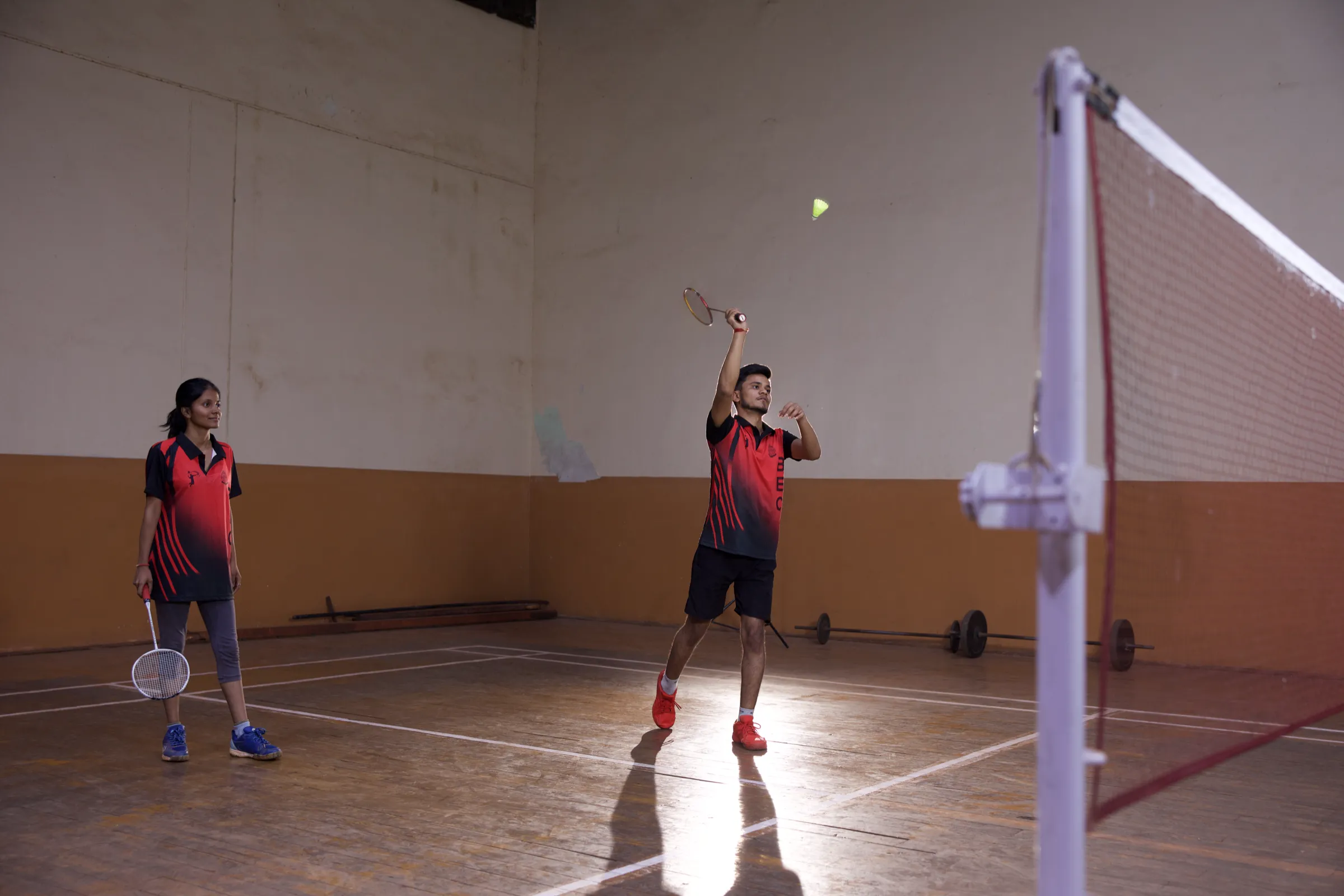 A BEC player leaps for an overhead smash during badminton in the indoor stadium
