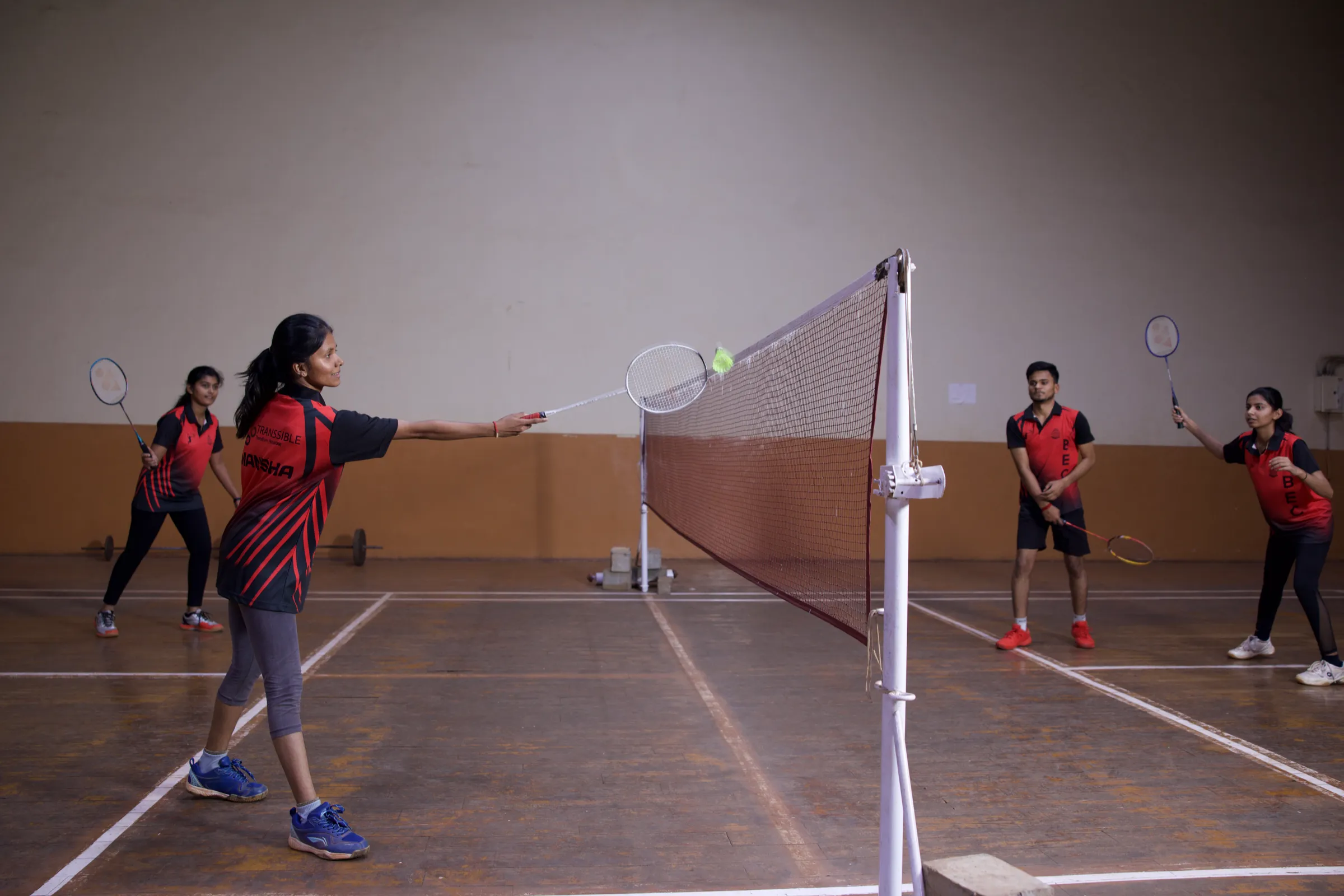 A doubles badminton rally at the net in the BEC indoor stadium
