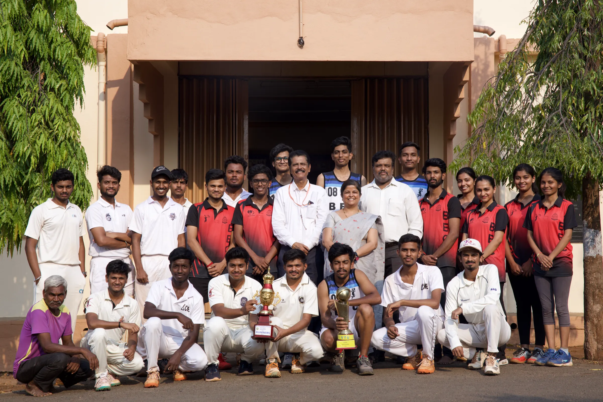 BEC sports teams and coaches with their trophies outside the gymkhana